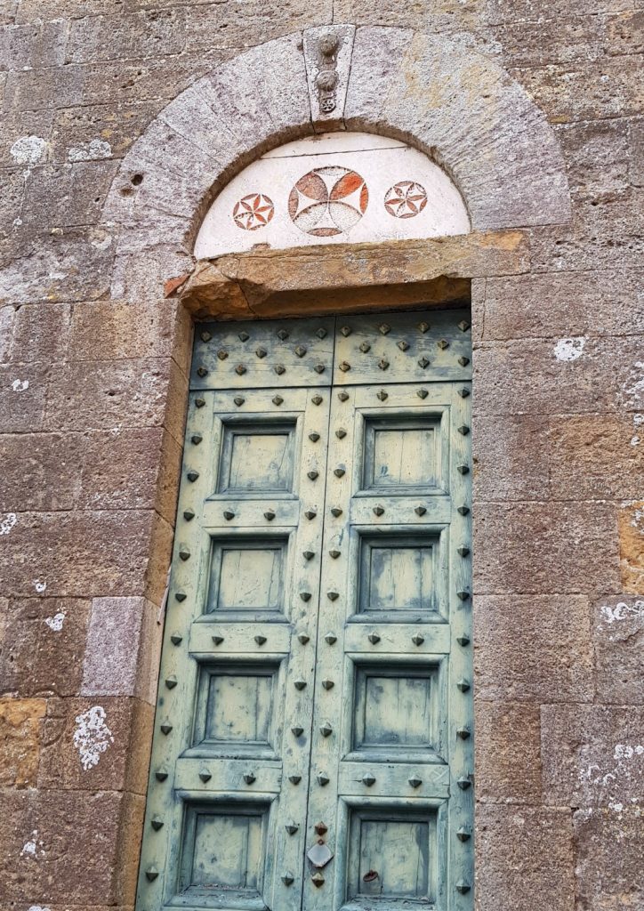 Ornate old green door topped with Maltese crosses in Volterra, near Villa Le Capanne in Tuscany - my review of the perfect big family villa in Tuscany, Italy