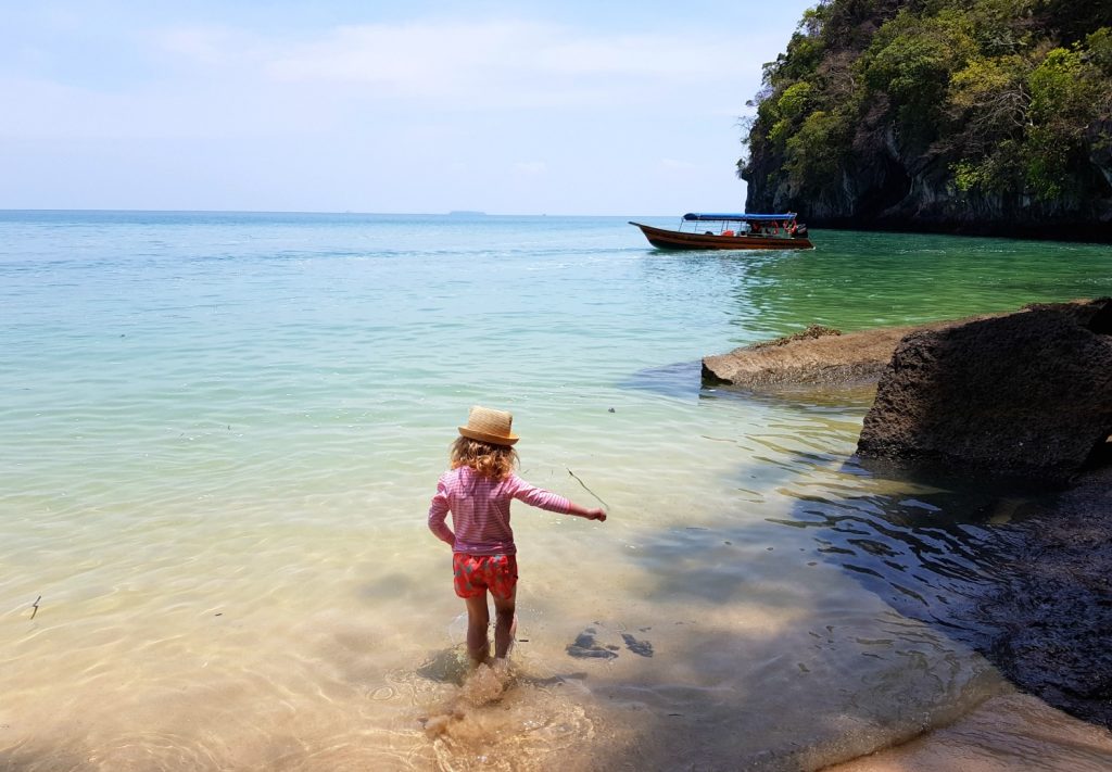 My daughter splashes in the sea off a small beach on Langkawi, boat in the background by the tree lined hills - my Ultrasun kids review and why I love this once-a-day formula