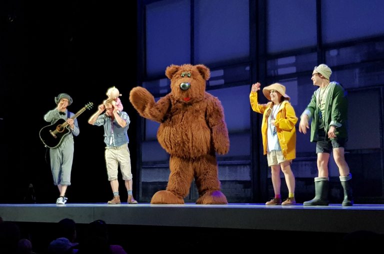The cast of We're Going on a Bear Hunt, including bear, on the stage at the Apollo Theatre during the preview for Kids Week London 2018, with discounts on children's tickets for West End shows