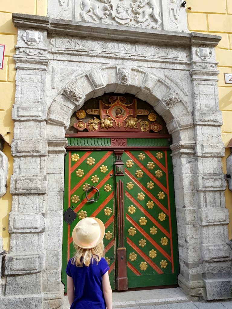 My daughter looks at the green, red and gold decorative door of the house of the Blackheads - the city's history is just one of the many reasons to visit Tallinn, Estonia