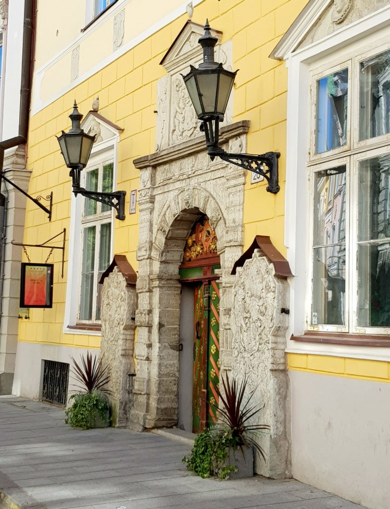 The yellow facade and glimpse of the paterned painted door of the House of the Blackheads - the city's history is just one of the many reasons to visit Tallinn, Estonia