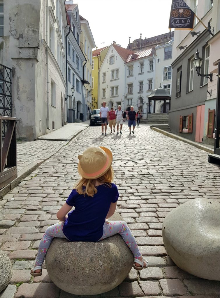 My daughter sits on one of the decorative stone shapes around the Old Town - the quirky details are one of the many reasons to visit Tallinn, Estonia