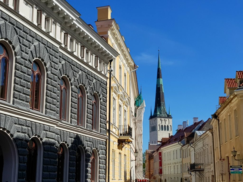 View around decorative buildings on a street corner to one of the Old Town's many spires - the city's famously fairytale architecture is just one of the many reasons to visit Tallinn, Estonia