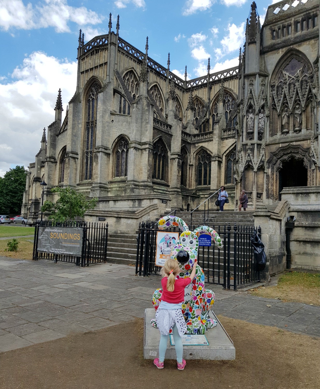 My daughter with a floral Gromit in front of a church - following the Gromit Unleashed 2 trail in Bristol, our review