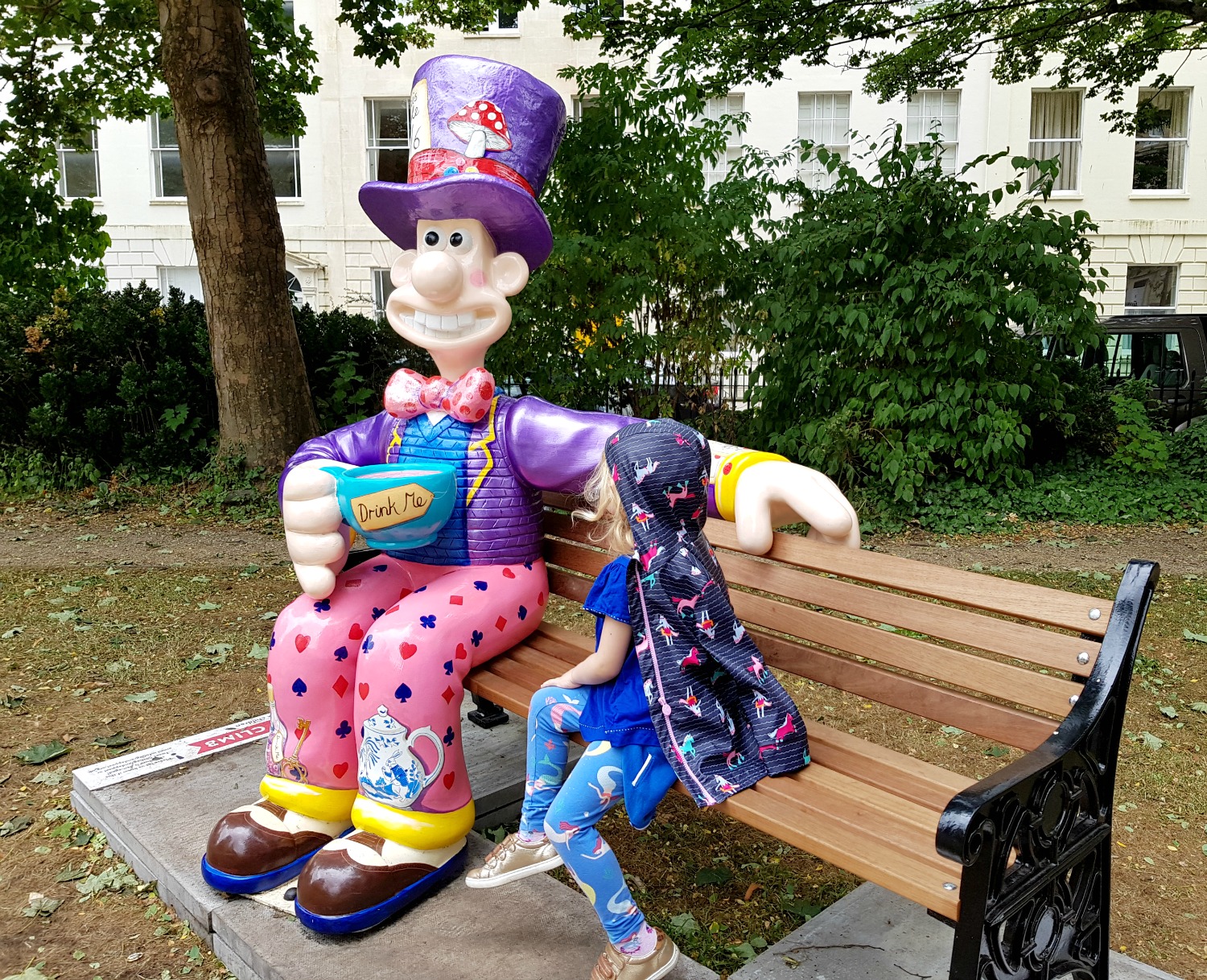 My daughter on the bench with Wallace in Wonderland, a brightly coloured Mad Hatter style statue - following the Gromit Unleashed 2 trail in Bristol, our review