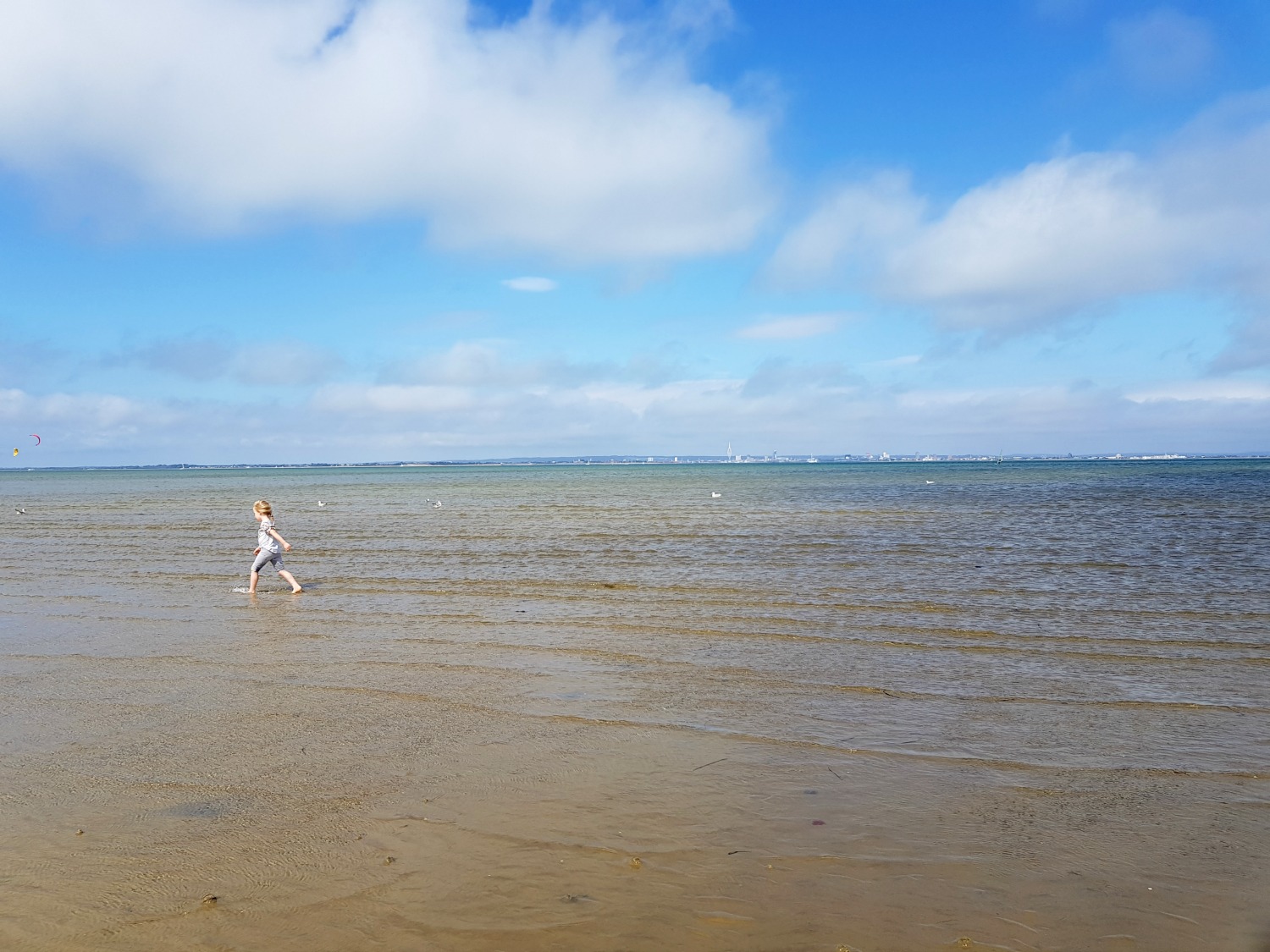 My daughter runs through the shallow water at the edge of the beach at Appley on the Isle of Wight