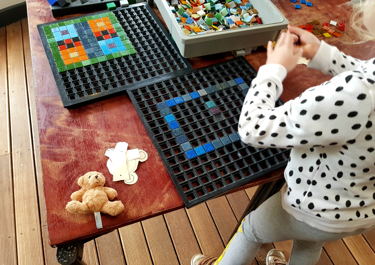 My daughter making a mosaic at Brading Roman Villa with her own bear and parts of a bear puppet on the table - an Isle of Wight bear hunt, exploring the island in the footsteps of the famous children's book