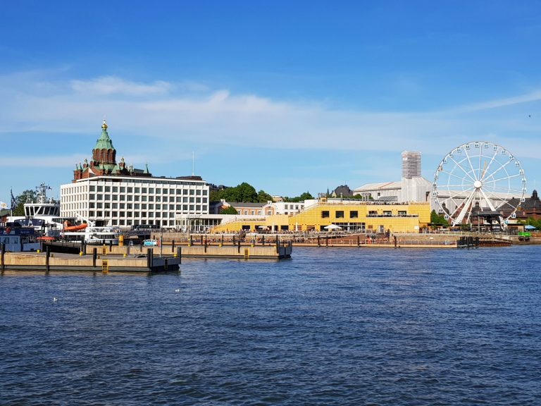 View across the water to the harbour, observation wheel and open-air pool in Helsinki - the architecture and chilled-out atmosphere is one of the top answers to the question why visit Helsinki?