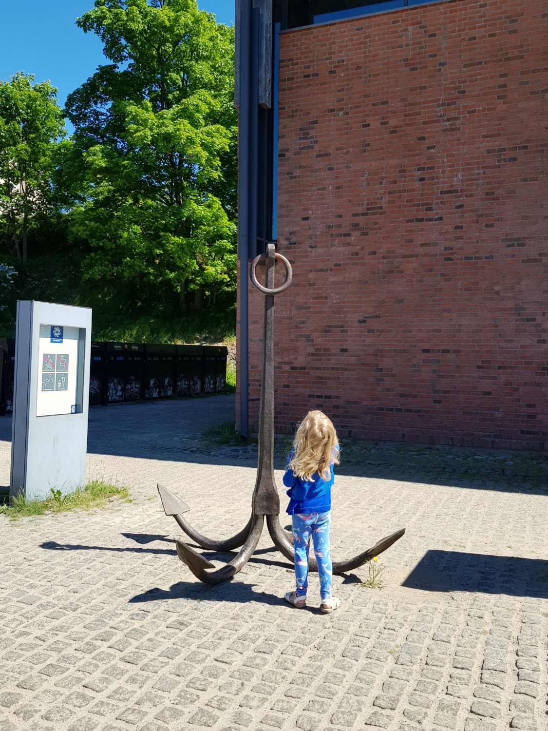 My daughter stands by a giant anchor outside Suomenlinna Museum on the island near the city of Helsinki - my tips on visiting Suomenlinna with kids