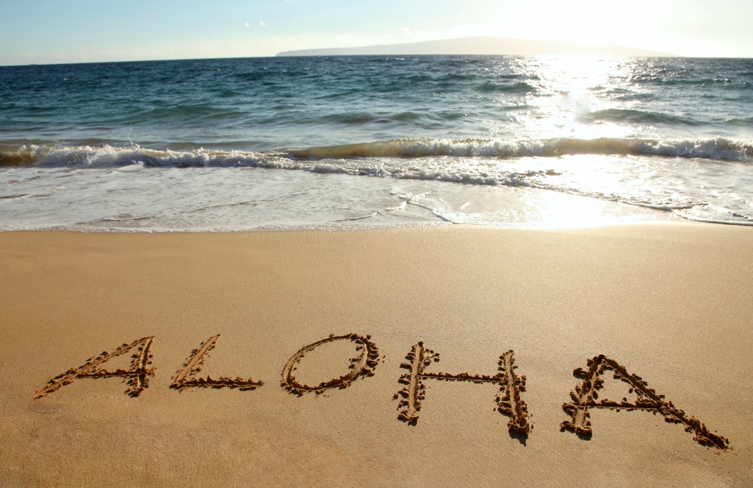 The word Aloha written in a sandy beach - planning a dream Hawaii trip with kids