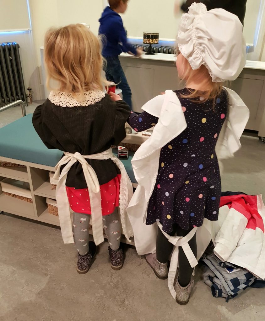 My daughter and a new friend dressed up and playing at housekeeper and servants with a plastic tea seat - my review of a free day out in London, visiting Gunnersbury Park Museum with kids