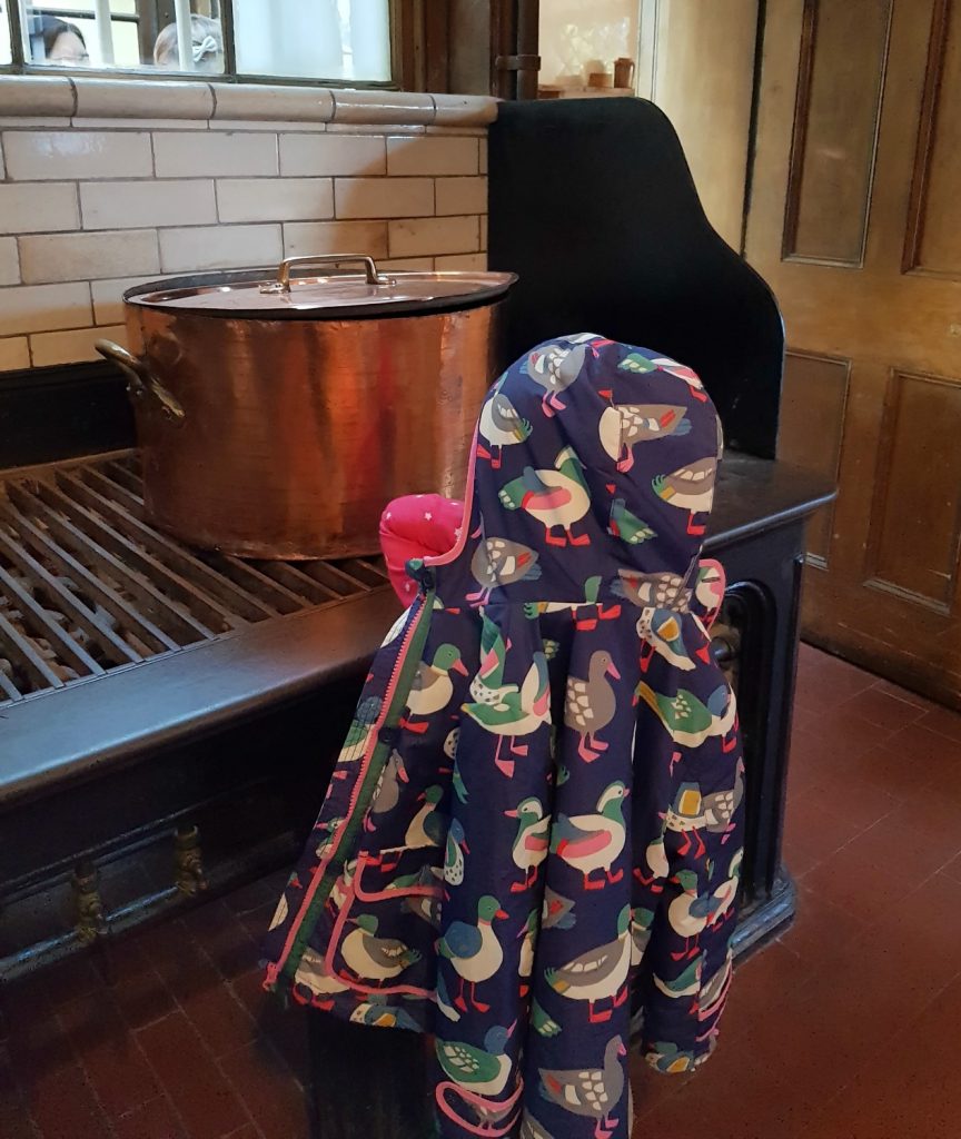 My six-year-old daughter in her winter coat next to a huge copper pot in the historic kitchens - my review of a free day out in London, visiting Gunnersbury Park Museum with kids