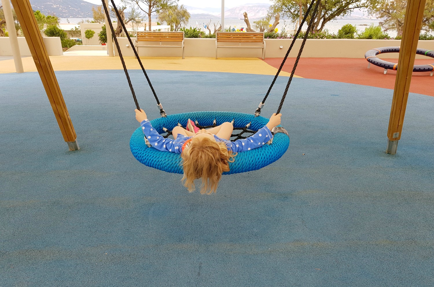My daughter swinging on the swing in the playground of Ikos Dassia - my review of Ikos Dassia with kids, a family holiday in Corfu