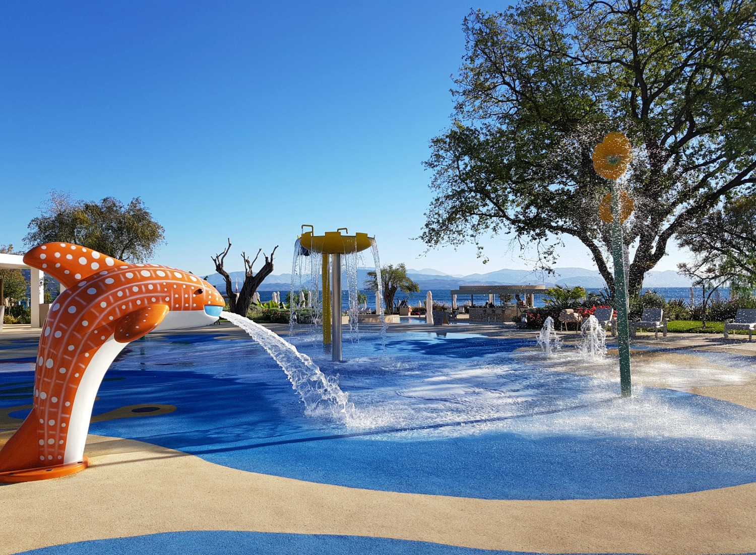Kids splashzone with water coming from the mouth of an orange dolphin at Ikos Dassia - my review of Ikos Dassia with kids, a family holiday in Corfu