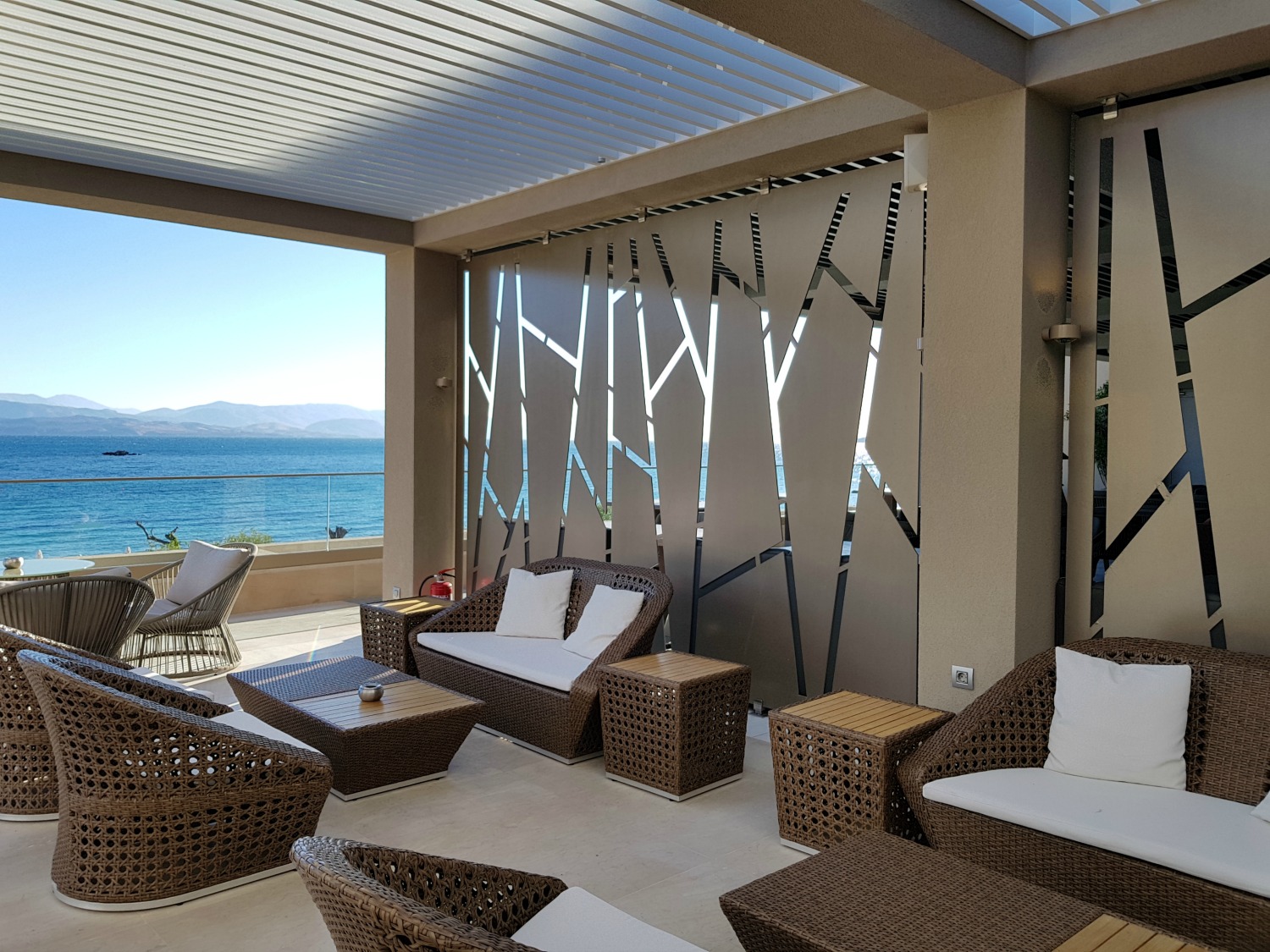 Comfortably outdoor chairs on a balcony in one of the lobby bars looking out to the sea at Ikos Dassia - my review of Ikos Dassia with kids, a family holiday in Corfu