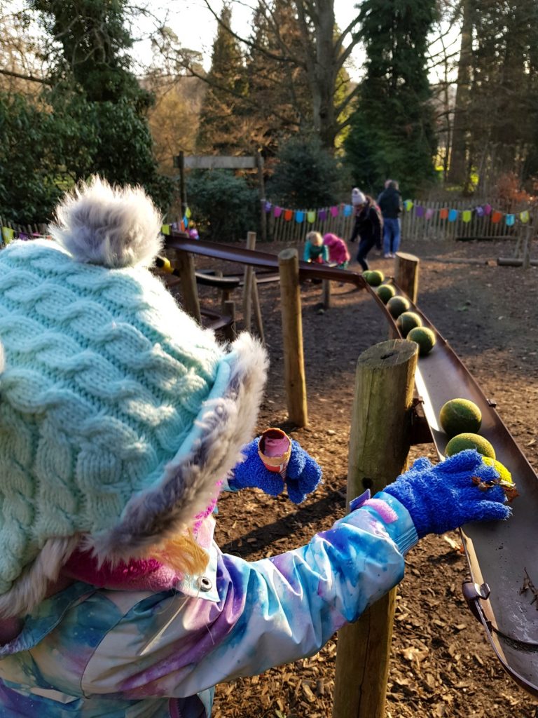 My daughter playing with tennis balls in the guttering run at the natural play area at Scotney Castle, Kent - our winter day out at Scotney Castle with kids