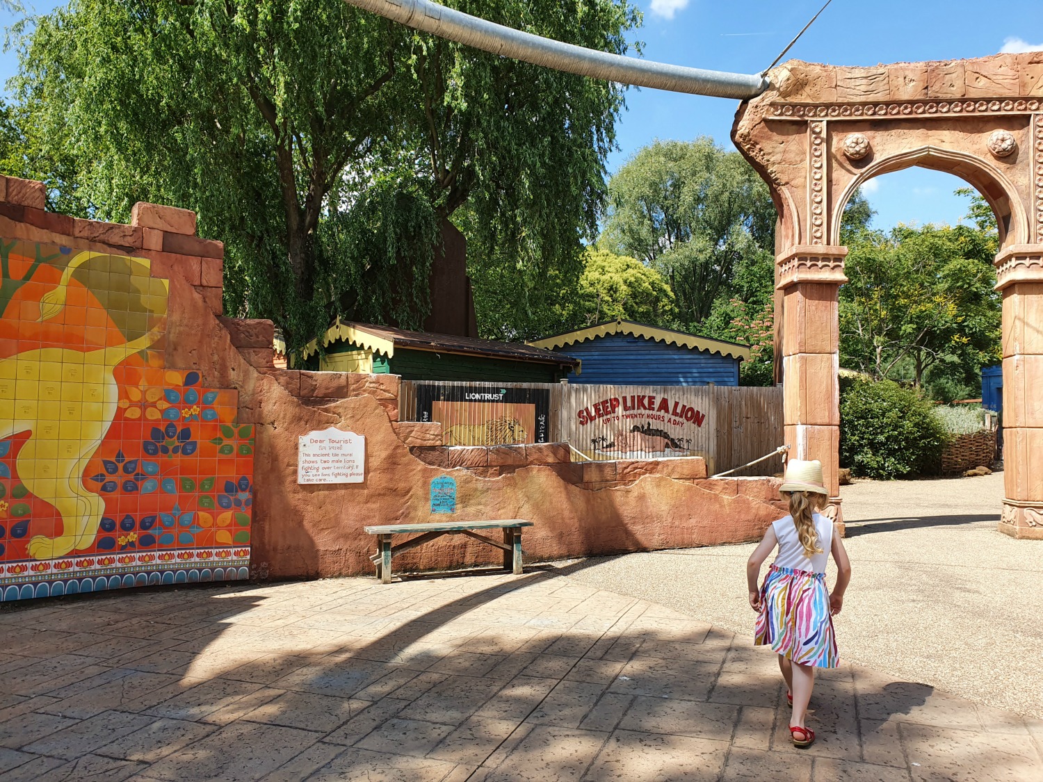 My daughter walks past brightly painted signs into the Land of the Lions at London Zoo