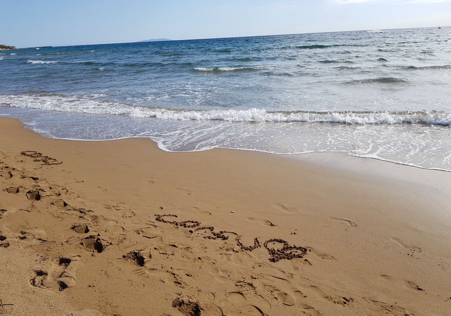 The word 'corfu' and a heart written in the sand at Issos beach - one day in Corfu exploring some of the island in an Ikos Dassia mini
