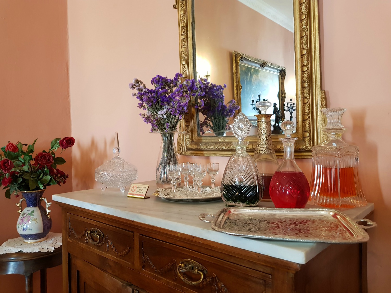 Decanters and flowers on a sideboard in Casa Parlante - one of my three things to do in Corfu Town with kids