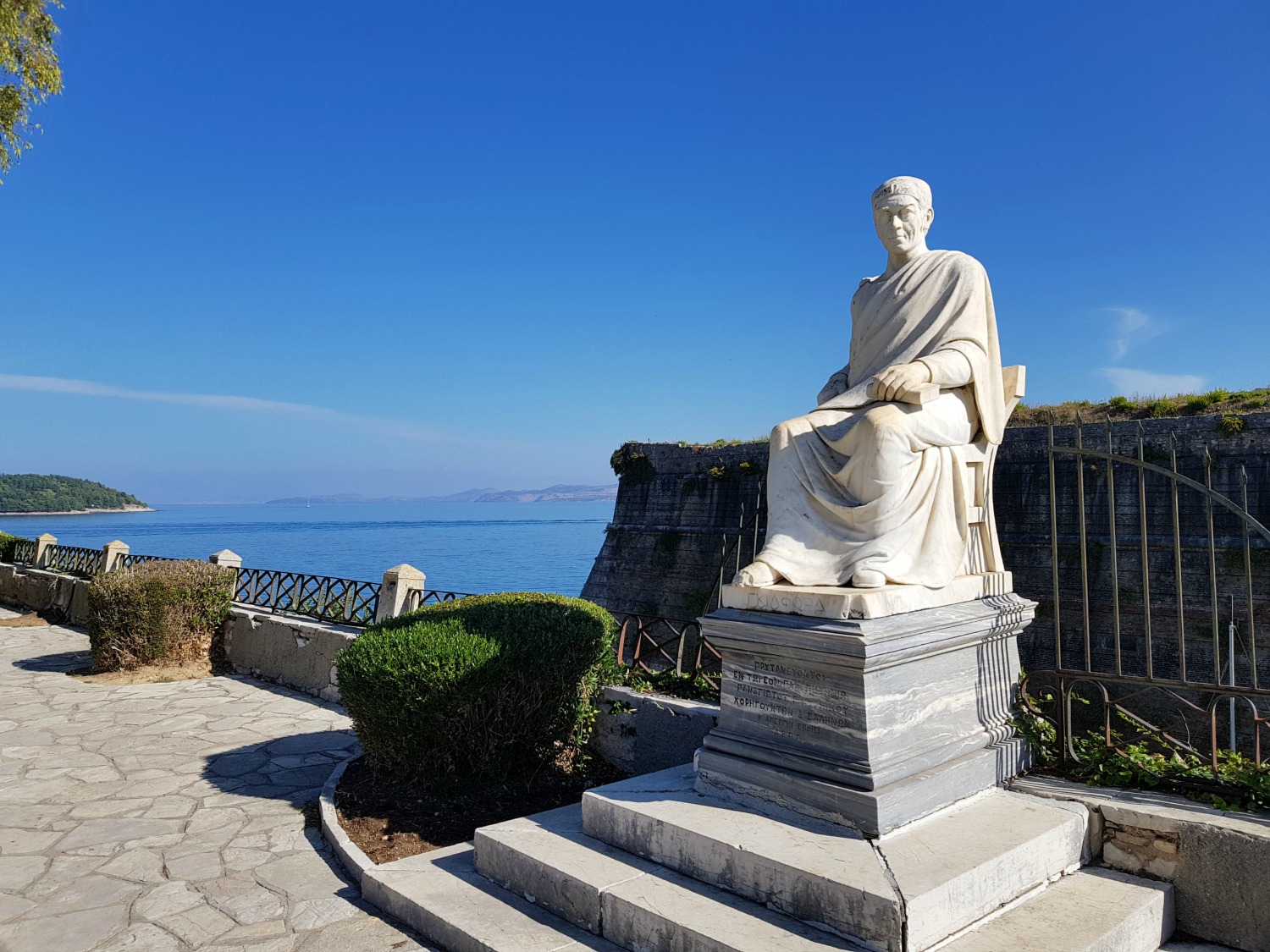 Marble statue with the sea behind near Corfu Town's old Venetian fortress - three things to do in Corfu Town with kids