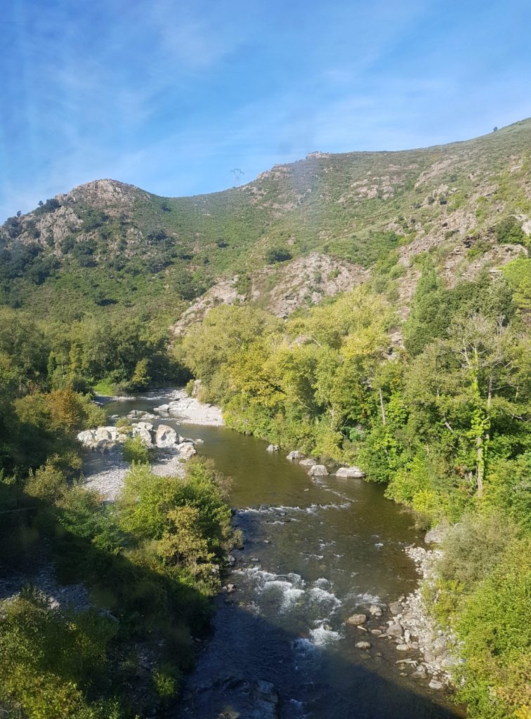 View of a river in a gorge from a train window on the line between Bastia and Calvi in Corsica - my Corsica short break visiting Bastia and Calvi in a long weekend