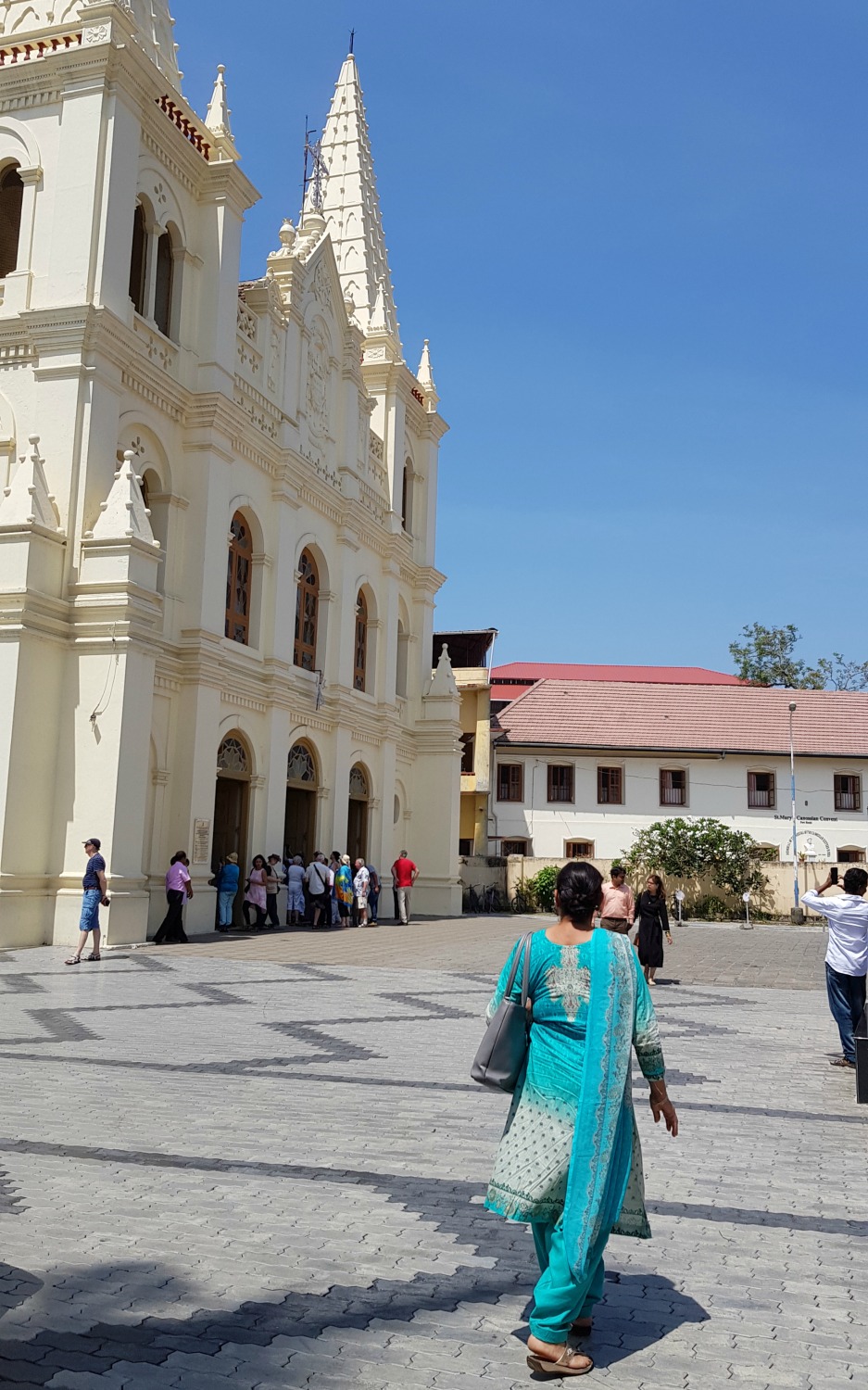 Woman in a green sari walks towards the Santa Cruz cathedral basilica in Fort Kochi - my one week in Kerala itinerary, including Kerala with kids