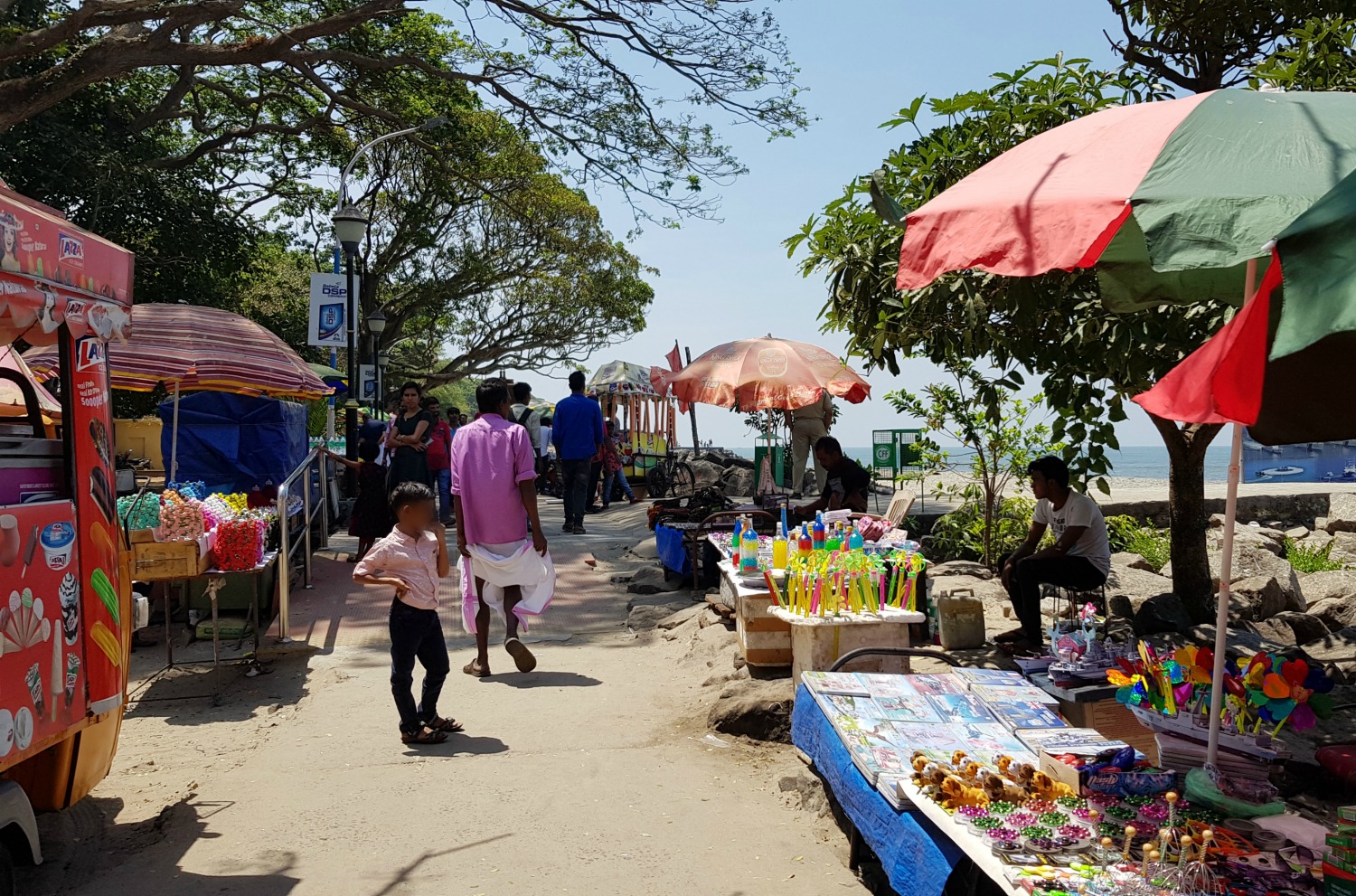 Locals walk along the seafront stalls in Fort Kochi - my one week in Kerala itinerary, including Kerala with kids