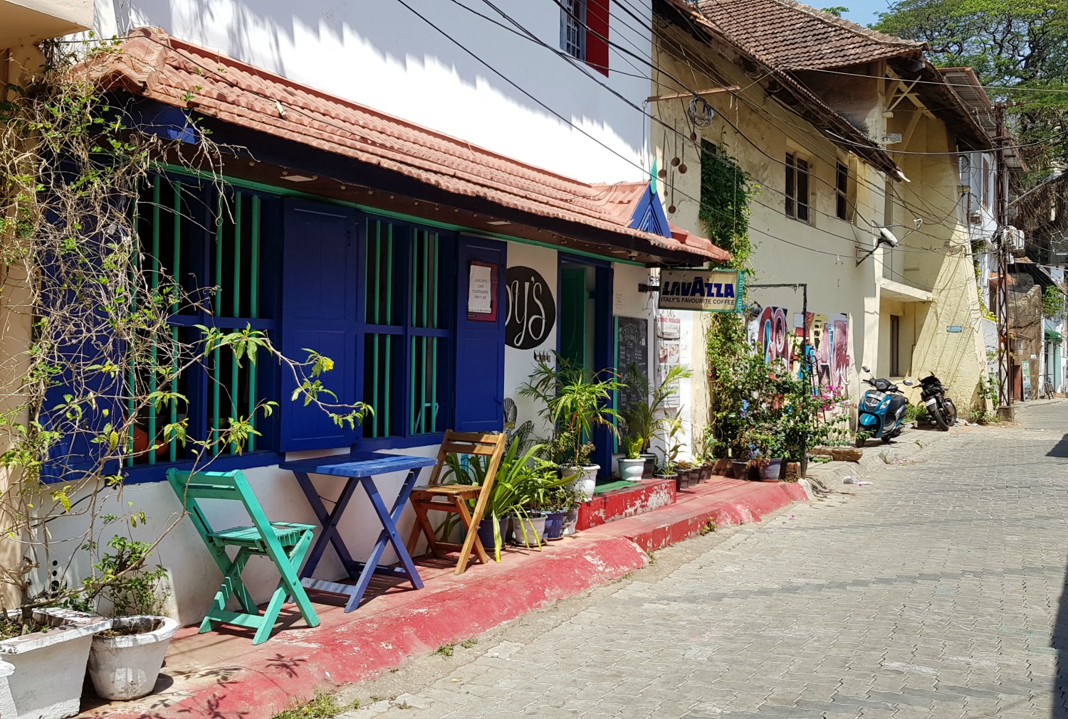 Tables outside a cafe in an alleyway with street art in Fort Kochi - my one week in Kerala itinerary, including Kerala with kids
