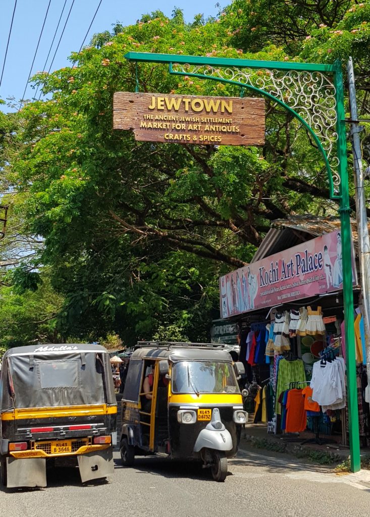 Tuktuks pass in the street under the sign for Jewtown in Mattancherry - my one week in Kerala itinerary, including Kerala with kids