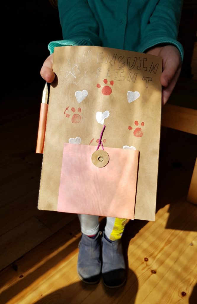 My daughter holds her finished printed notebook after the activity session at Penhein