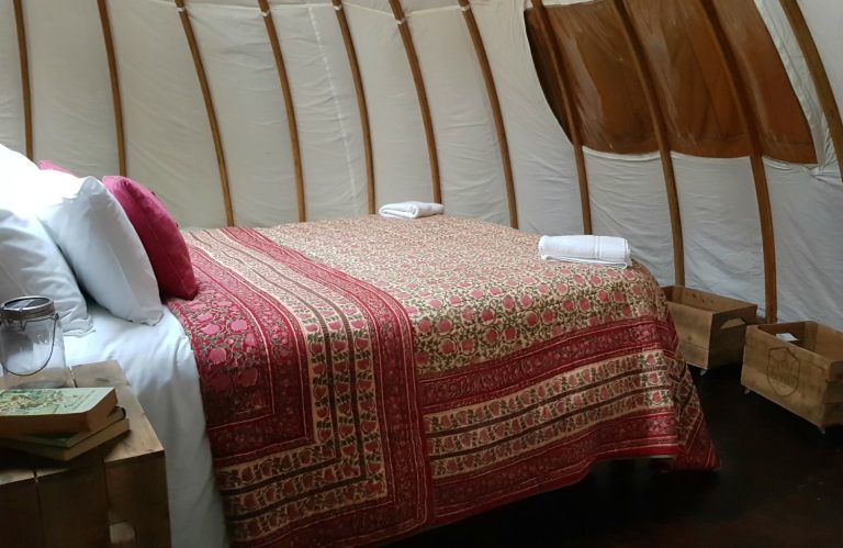 View of the bed and inside of the alachigh tent at one of Wales' luxury glamping sites - my Penhein glamping review