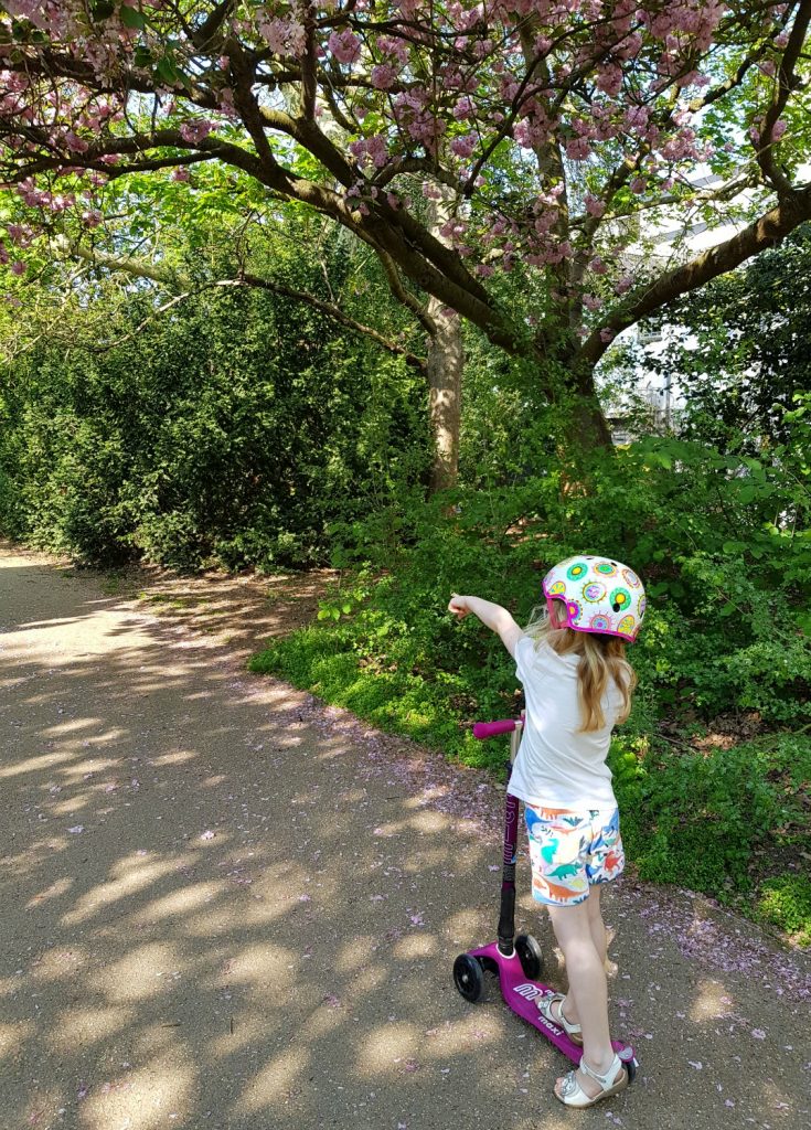 My daughter pointing into the distance as she scoots along a path