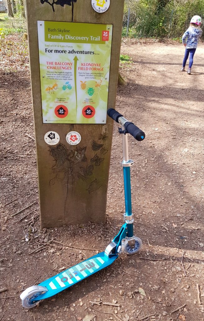 Micro Sprite scooter on its kickstand next to a sign on the Bath Skyline Family Discovery trail