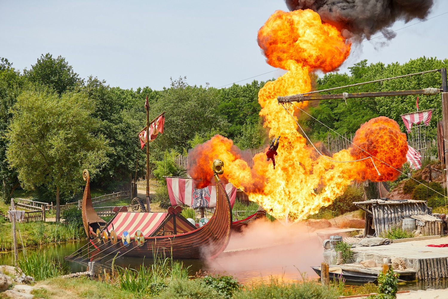 Pyrotechnics behind a Viking Ship as one of the actors flies through the air in Les Vikings show at Puy du Fou, France - my tips for Puy du Fou with kids