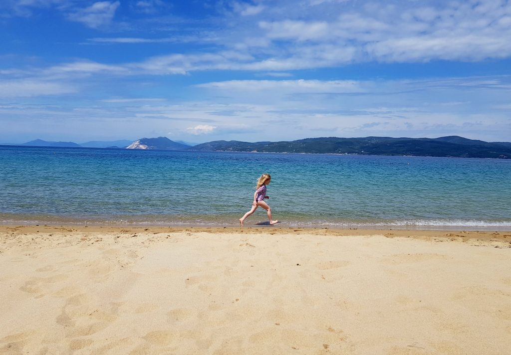 My daughter runs along the beach by our hotel in Skiathos, Greece - one of our May travel highlights