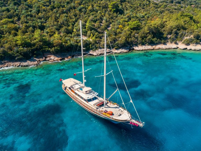 A gulet close to the wooded shore on turquoise sea - my tips for taking a family gulet cruise in Turkey