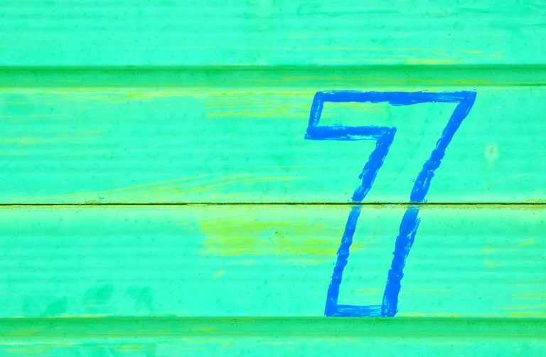 Blue painted number 7 on a turquoise painted metal background - looking back on seven years of travel with a child