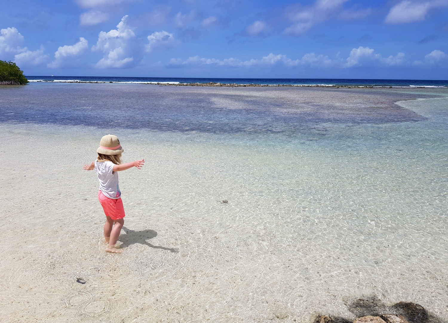 My daughter splashes in the clear water at Mangel Halto beach in Aruba - my Aruba tips, including why you'll only really need casual clothes and swimwear