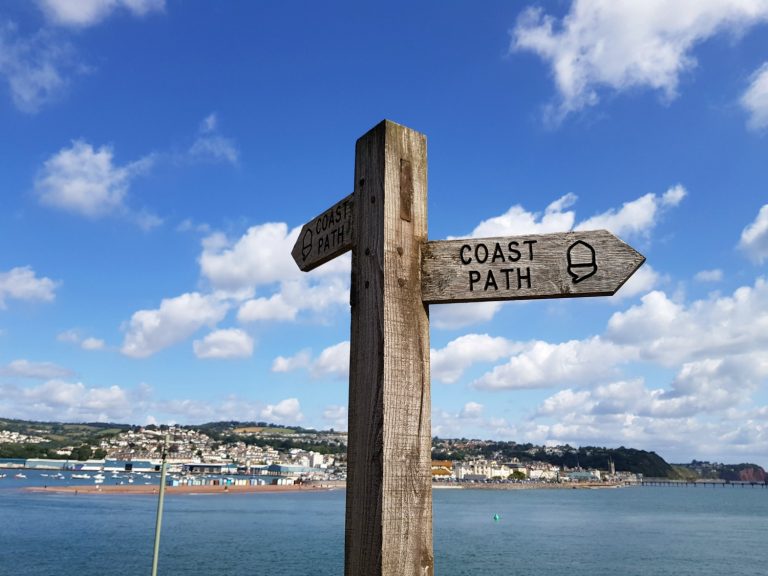 Sign for the South West coast path at Shaldon in Devon, with the see behind and Teignmouth in the distance - one day in Teignmouth and Shaldon with kids