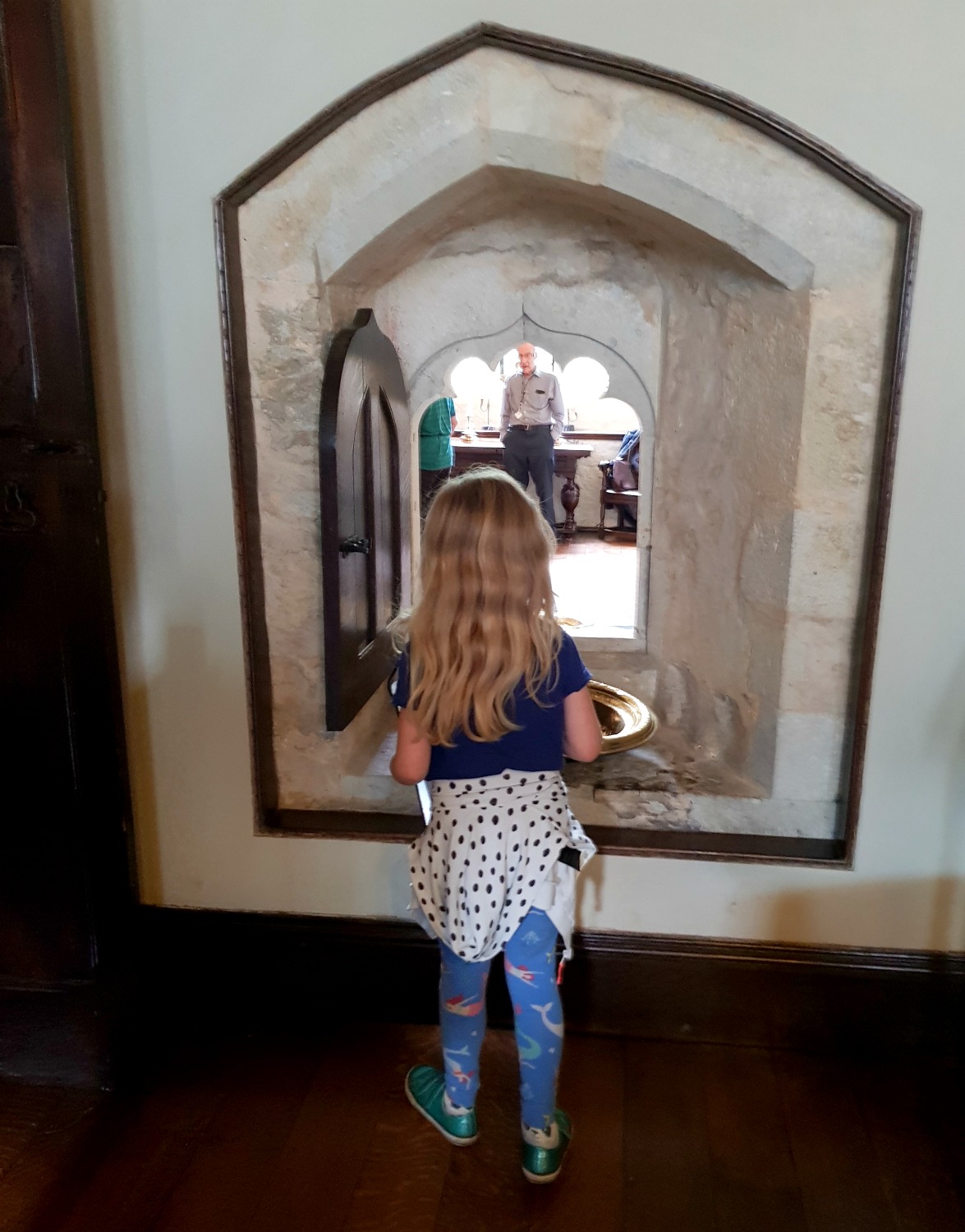 My daughter looks through an opening in the stone walls into another room at Ightham Mote in Kent