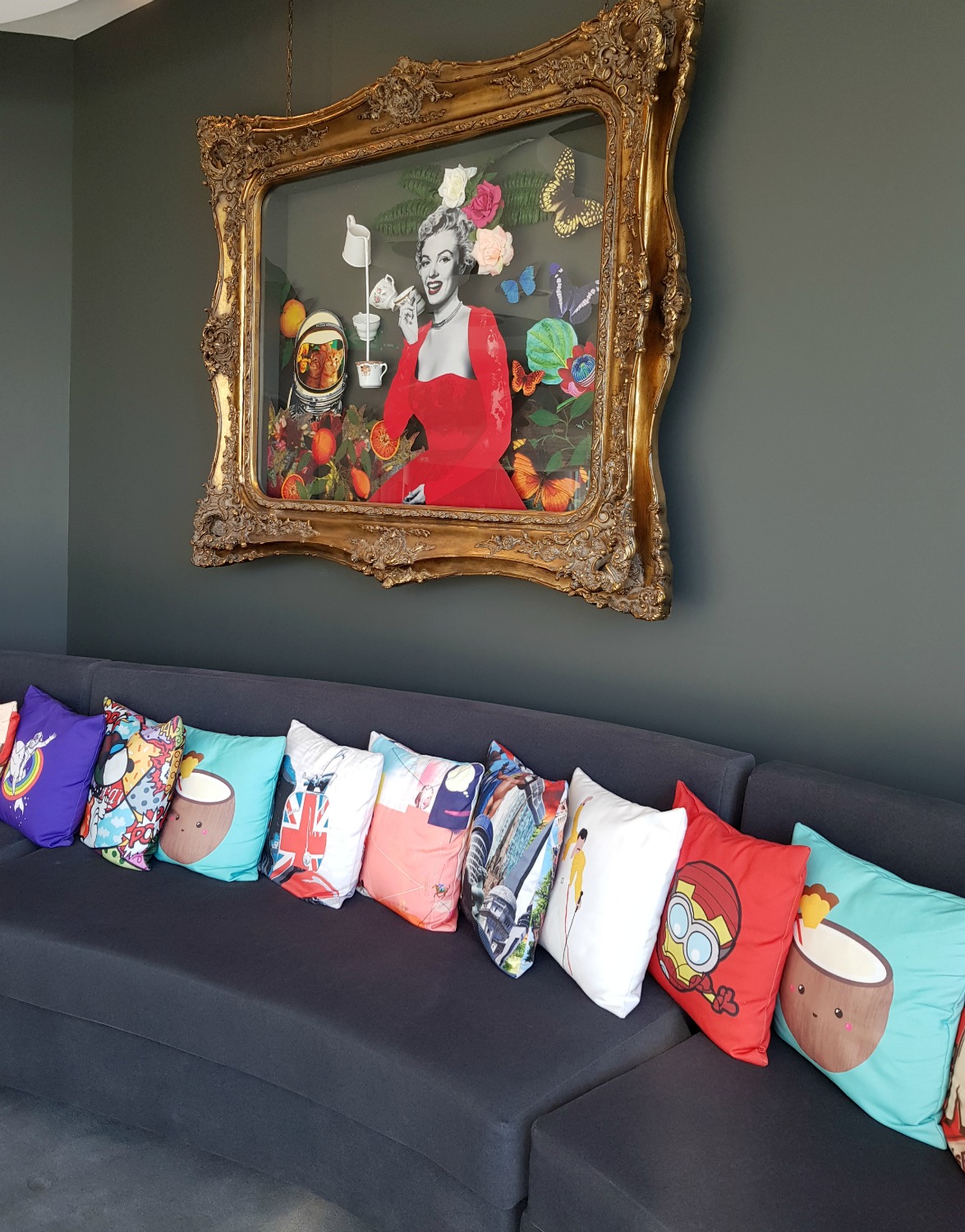 Framed picture of Marilyn Monroe in a red dress above seating area with brightly coloured cushions in the bar in Collage restaurant at the Radisson Blu Birmingham hotel