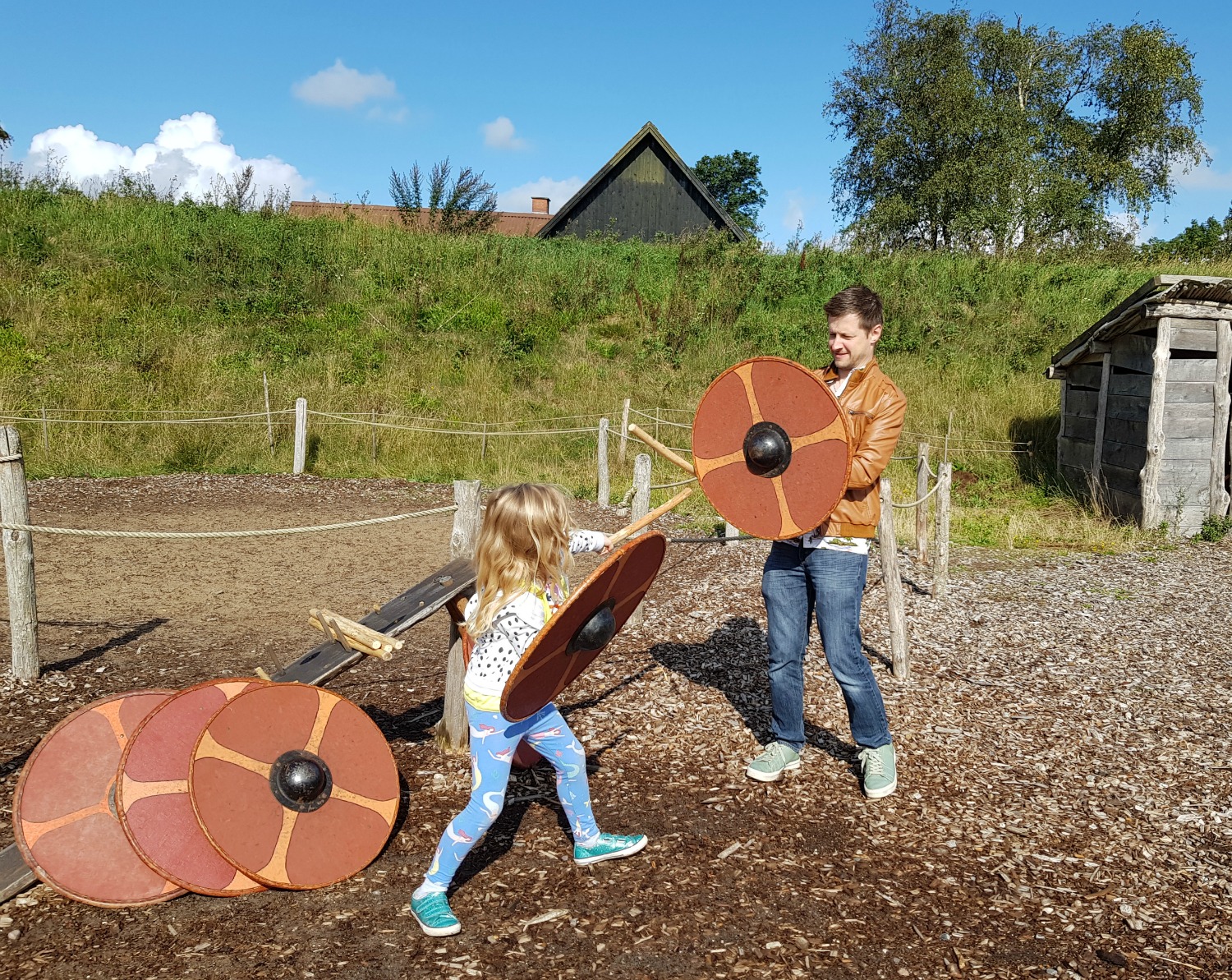 My daughter and husband play fight with Viking swords and shields at the Ribe Vikingecenter, one of my top places to visit during a week in Jutland with kids