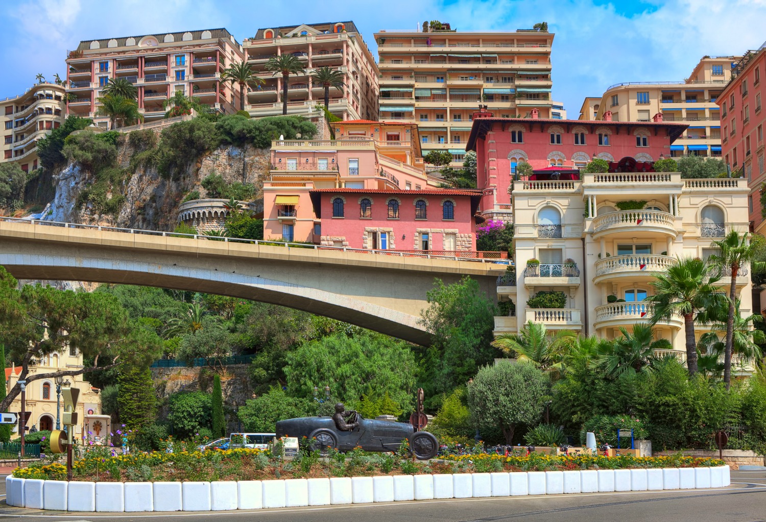 Sculpture of William Grover-Williams in Bugatti racing car, the first winner of Monaco Grand Prix on April 14, 1929 in the centre of a Monte Carlo roundabout, with colourful buildings in the background - visiting Monaco with kids