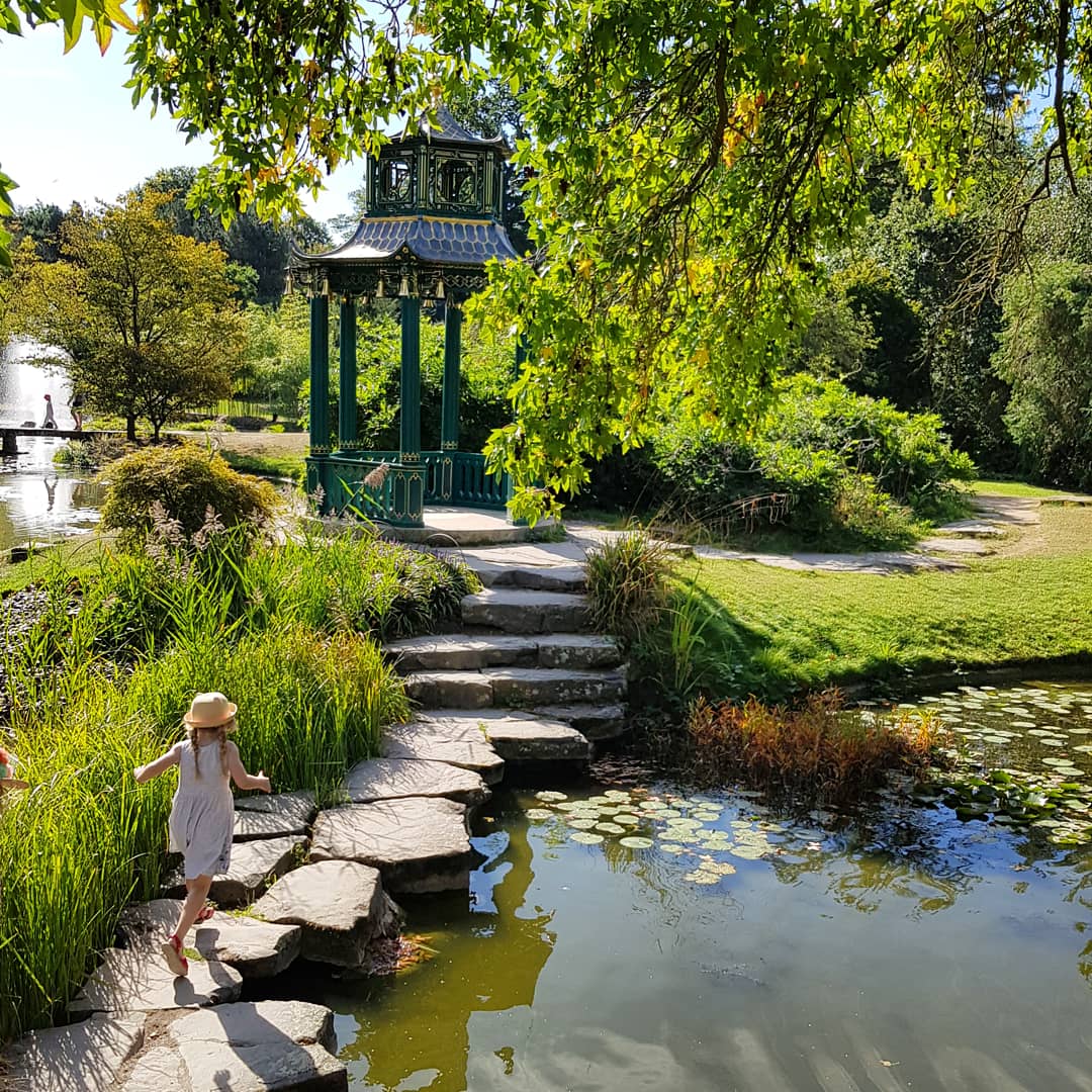 My daughter hops across stepping stones in the gardens of the grounds at Cliveden National Trust property - one of my September travel highlights