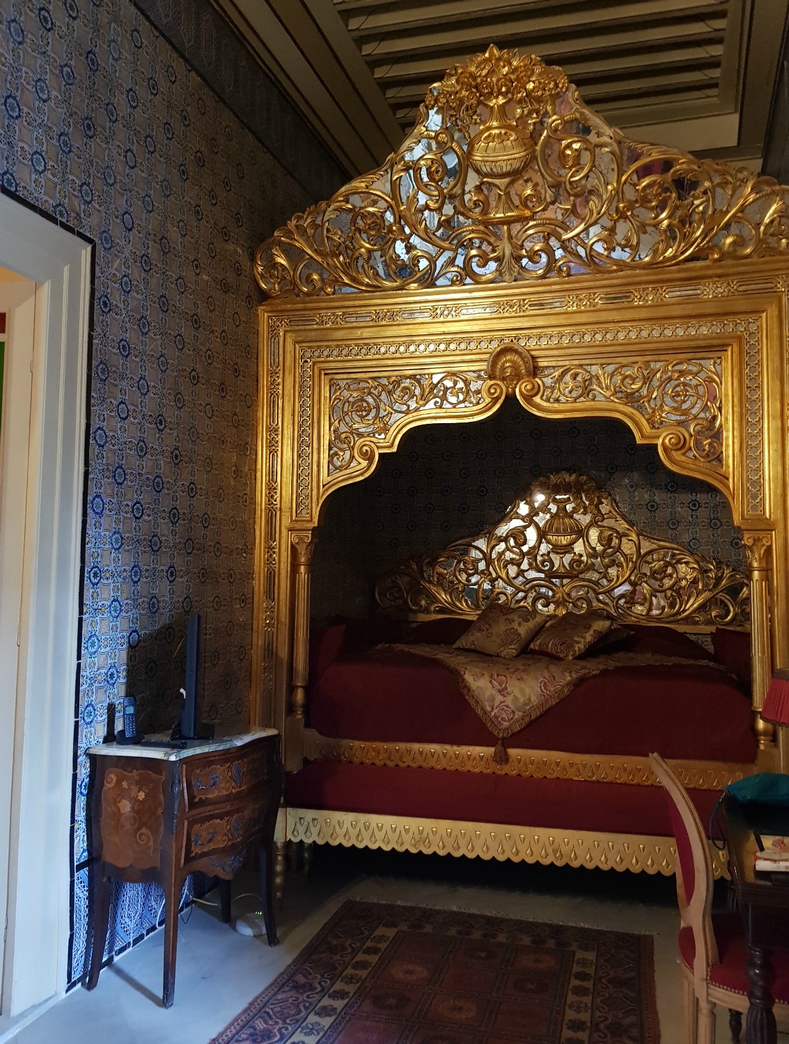 The bed in Kheireddin Pacha grand historic suite at Palais Bayram, with its gold arch - a stay at a boutique hotel in Tunis