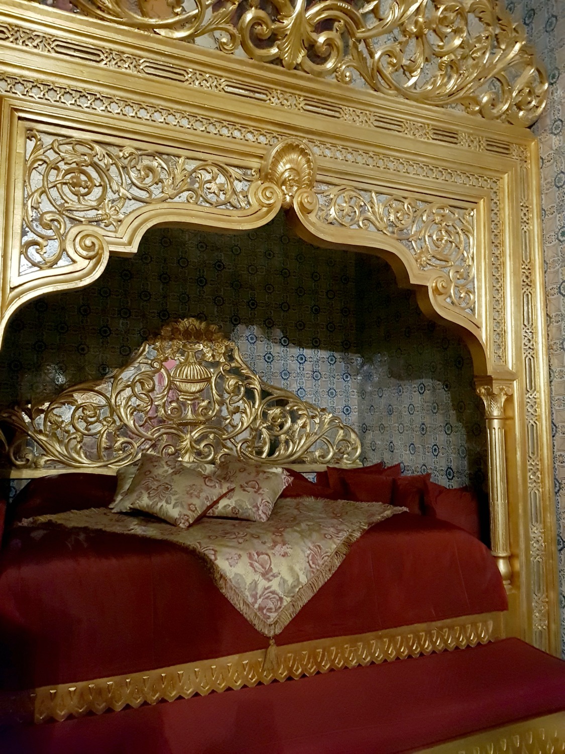Close-up view of the gold and red bedcovers in one of the canopy beds of Kheireddin Pacha grand historic suite at Palais Bayram, under a gold arch - my review of Palais Bayram boutique hotel in Tunis