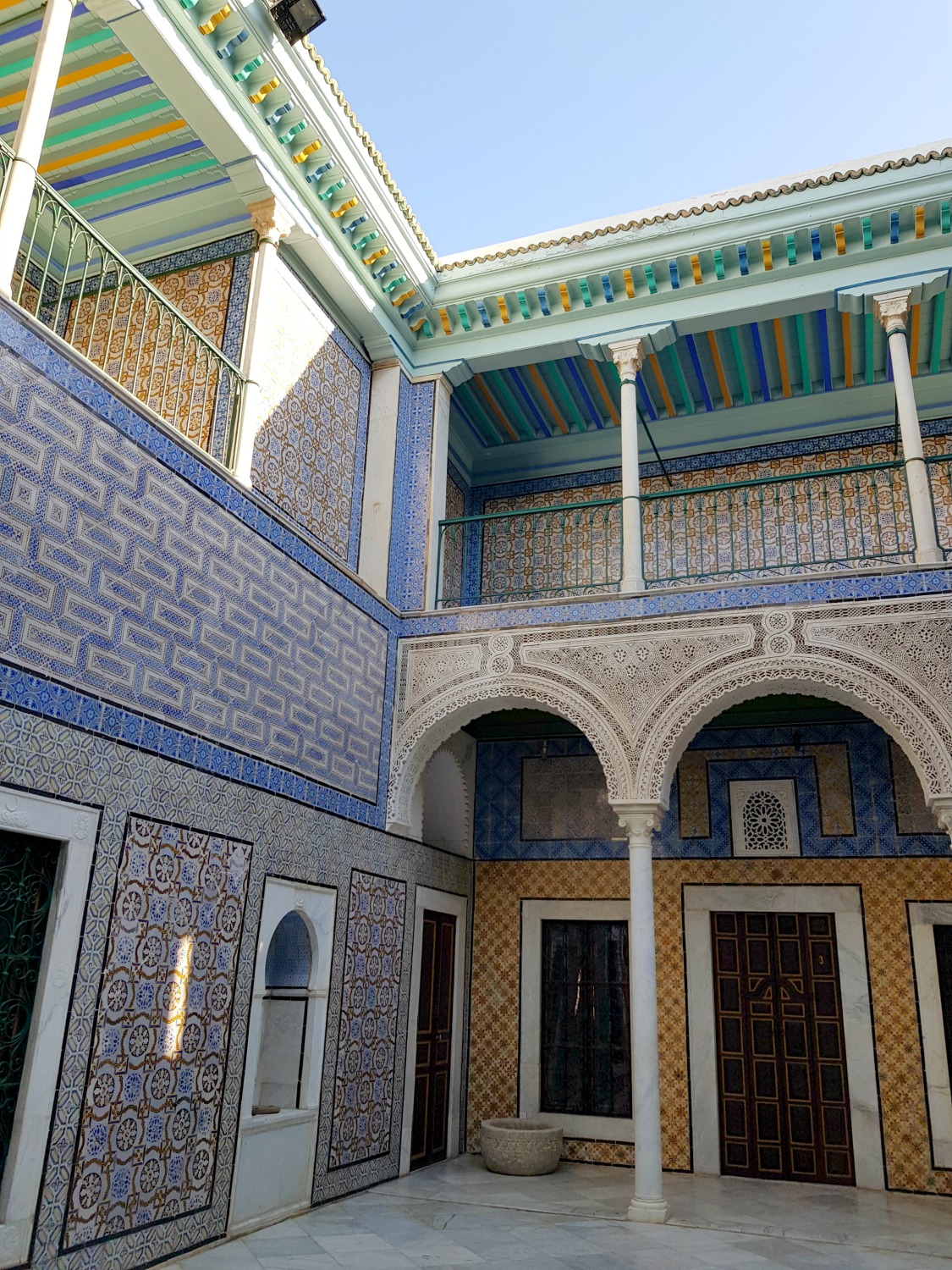 The tiled courtyard in the heart of Palais Bayram, with its blue and yellow tiles, while pillars and green painted sections on the roof - my Palais Bayram Tunis hotel review