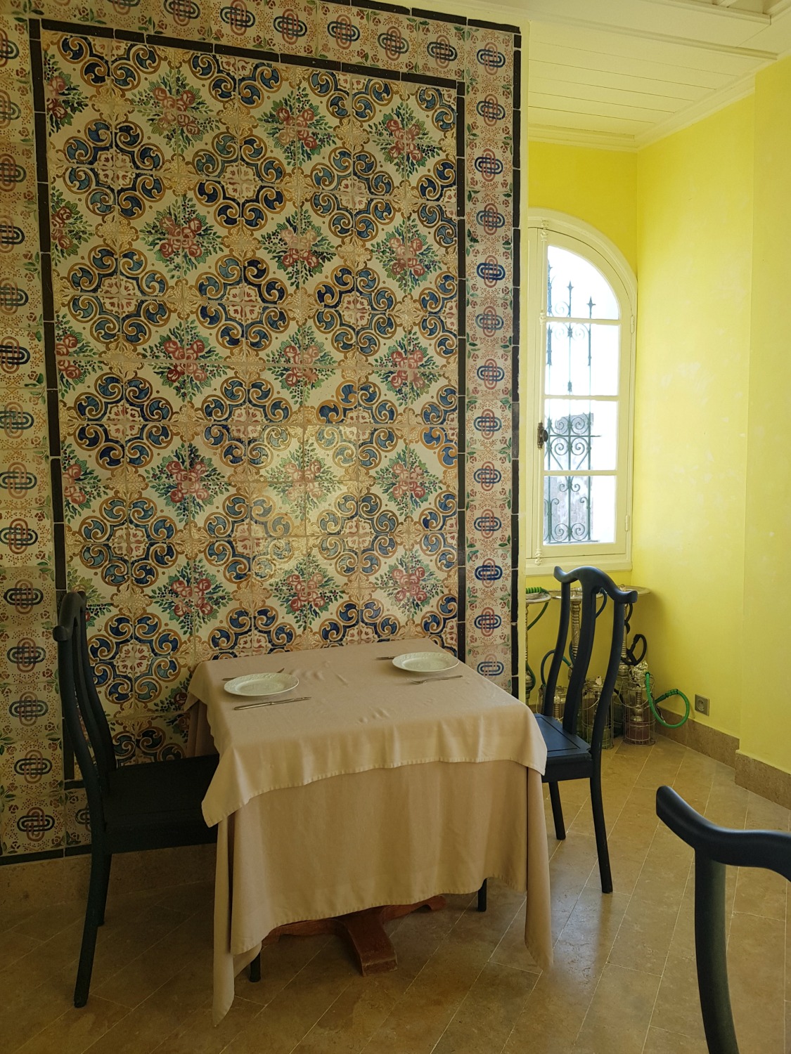 Tiled room in the tea house at Palais Bayram with shisha on the floor and yellow painted walls