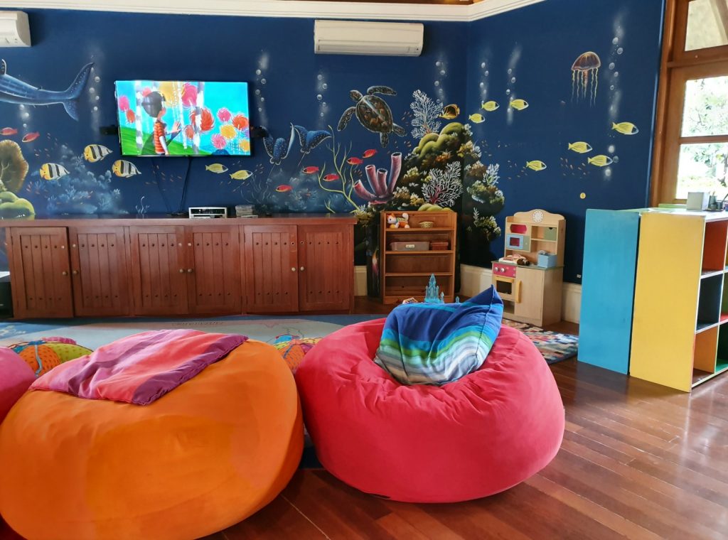 Bean bags in front of a TV and walls decorated with fish at the kids club at Kuda Huraa, one of the Four Seasons Maldives resorts