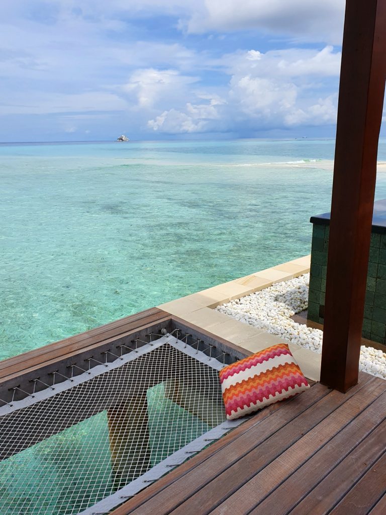 View of a cushion by one section of net on our water villa deck and the Indian Ocean in the background plus one small sandbank - a stay at Four Seasons Kuda Huraa with kids in the Maldives